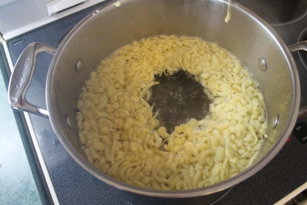 Spaetzle noodles floating to the surface of a pot of boiling water. 