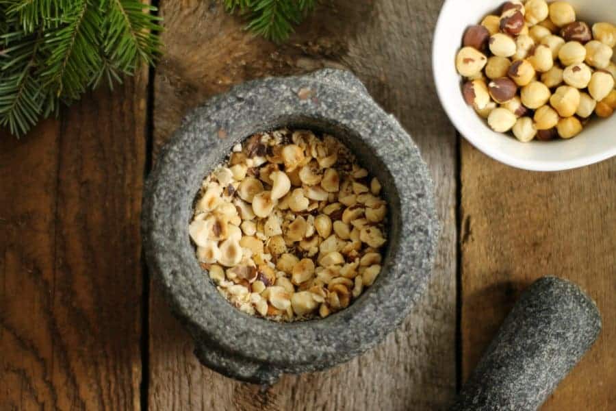 A bowl of crushed toasted hazelnuts in a mortar and Pestel on a barn board background