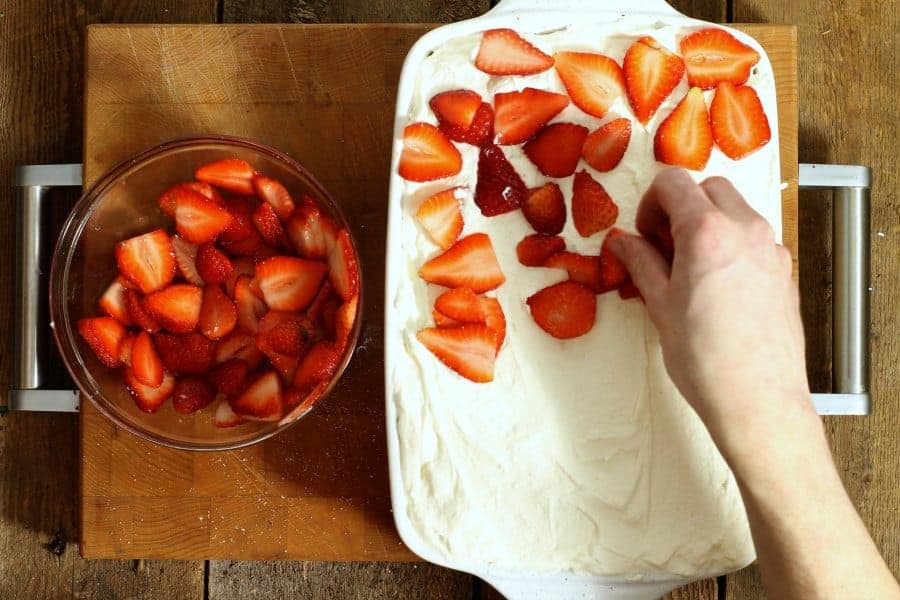 Layering sliced macerated strawberries on top of mascarpone cream for the strawberry tiramisu