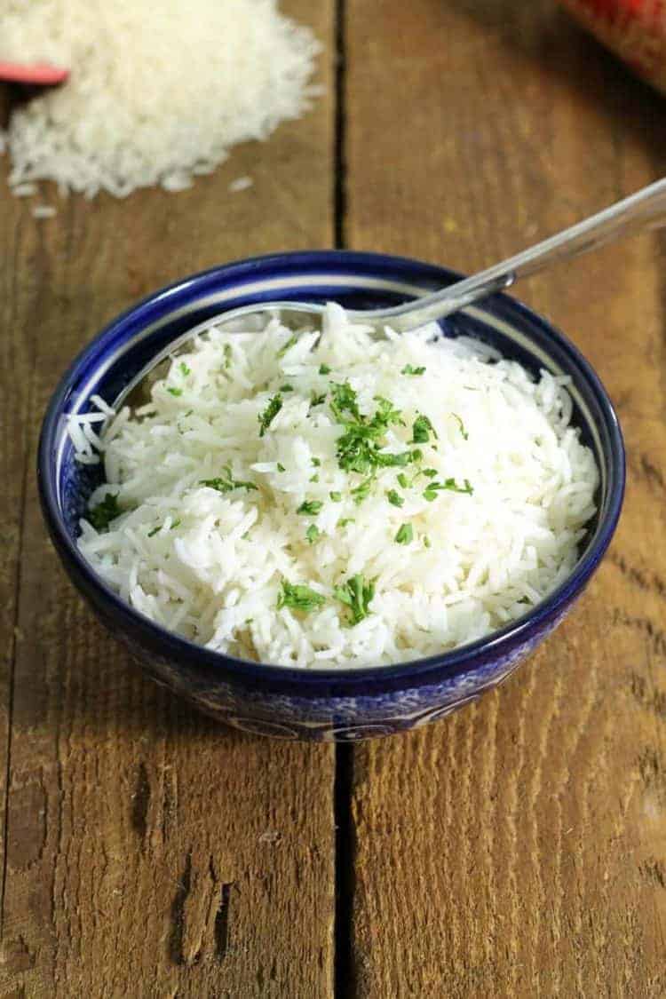 perfectly cooked basmati rice in a blue porcelain bowl garnished with chopped parsley