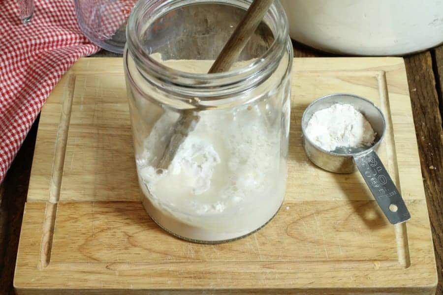 Mixing flour and water in a glass jar to make sourdough starter from scratch