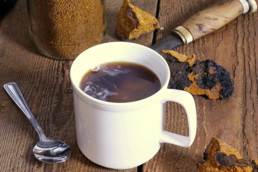 freshly brewed chaga tea in a white mug on a wooden table
