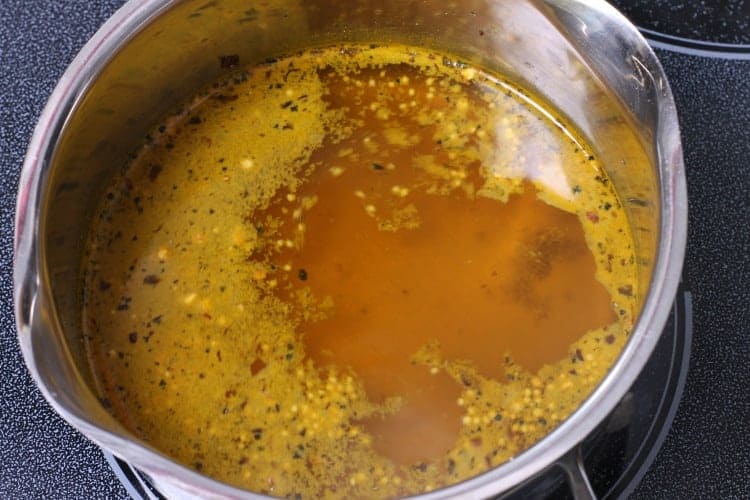 Vinegar, sugar, and various spices used to make refrigerator bread and butter pickles simmering in a pot.