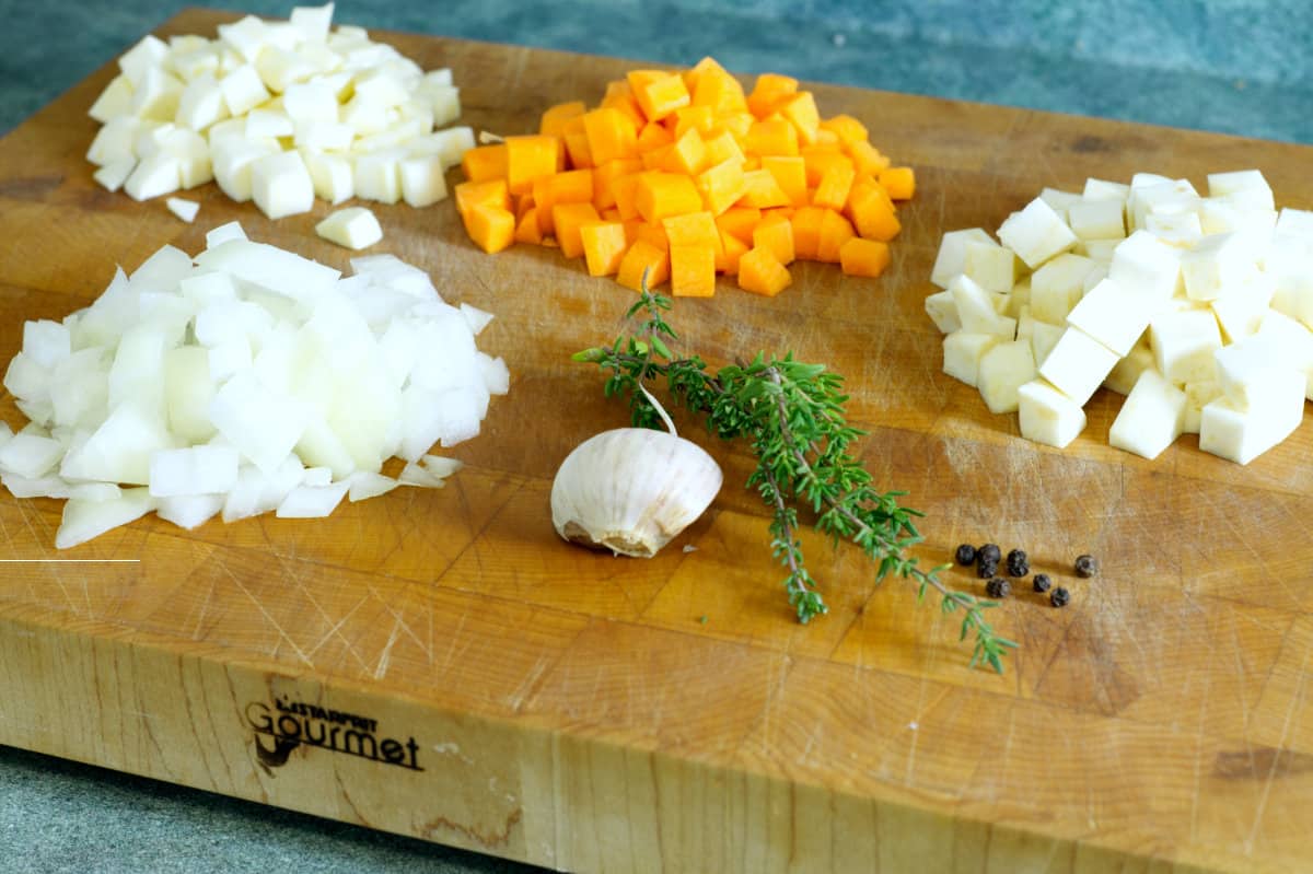 diced onion, carrot, parsnip, and celery root on a cutting board