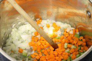 onions, carrot, and celery being sauteed in a pot with oil.