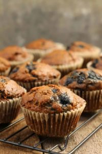 vertical image close close up of a blueberry bran muffin on a black cooling rack