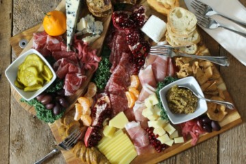 A rustic, holiday themed charcuterie platter on a wood board surface