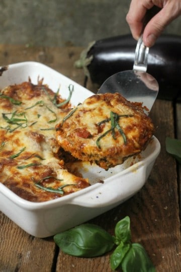 Baked layered eggplant parmesan being served from casserole with a metal spatula