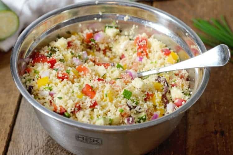 A metal bowl of Mediterranean Couscous Salad ready to be eaten or stored as meal prep