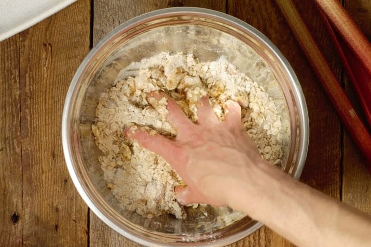 mixing ingredients by hand in a steel bowl to make crumble topping