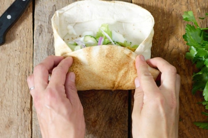 an image showing to to properly fold a naan wrap