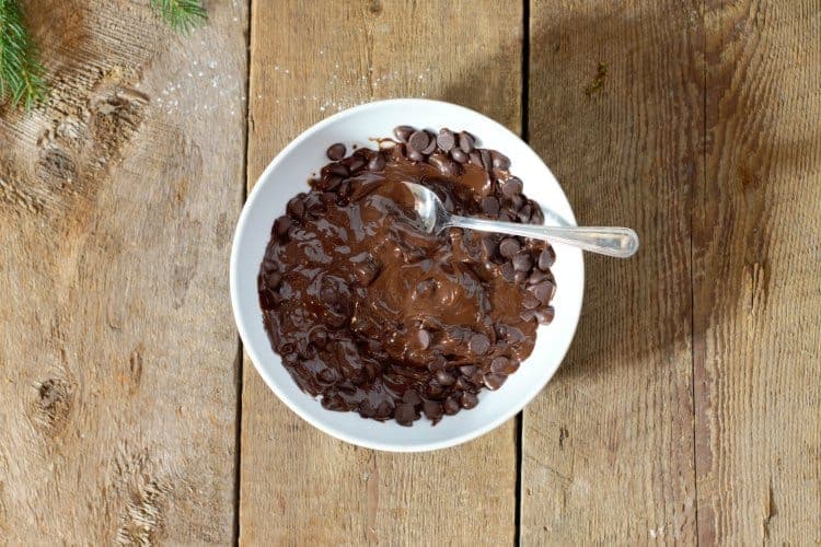 dark chocolate chips being melted in a white bowl