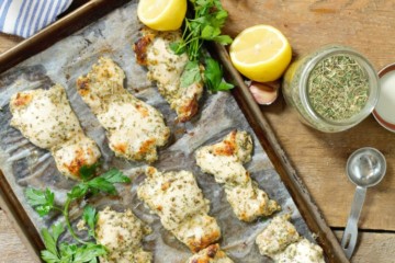 overhead shot of greek marinated chicken thighs on a sheet pan surrounded by various seasonings