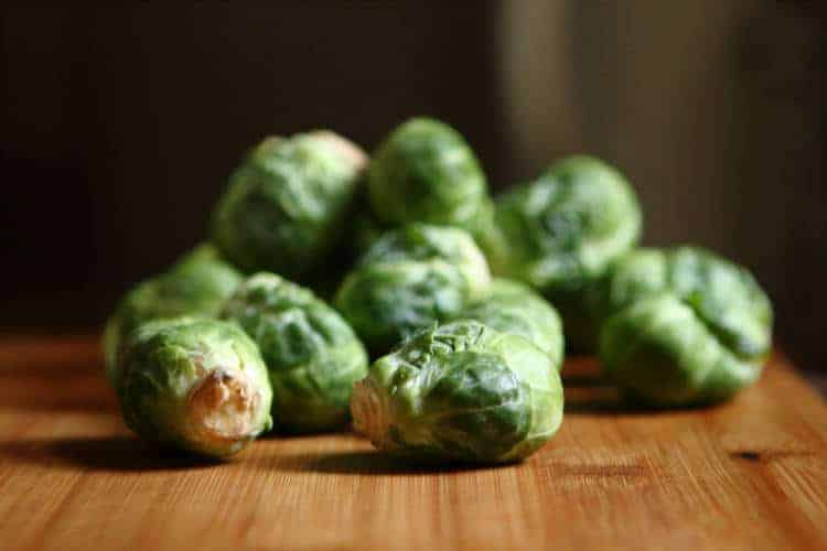 individual raw brussel sprouts on a wood surface