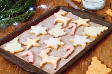 simple festive sugar cookies on a baking tray on a rustic wooden counter.