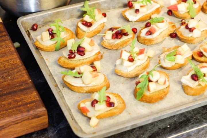 fully garnished warm brie crostini's on a sheet pan ready to be served