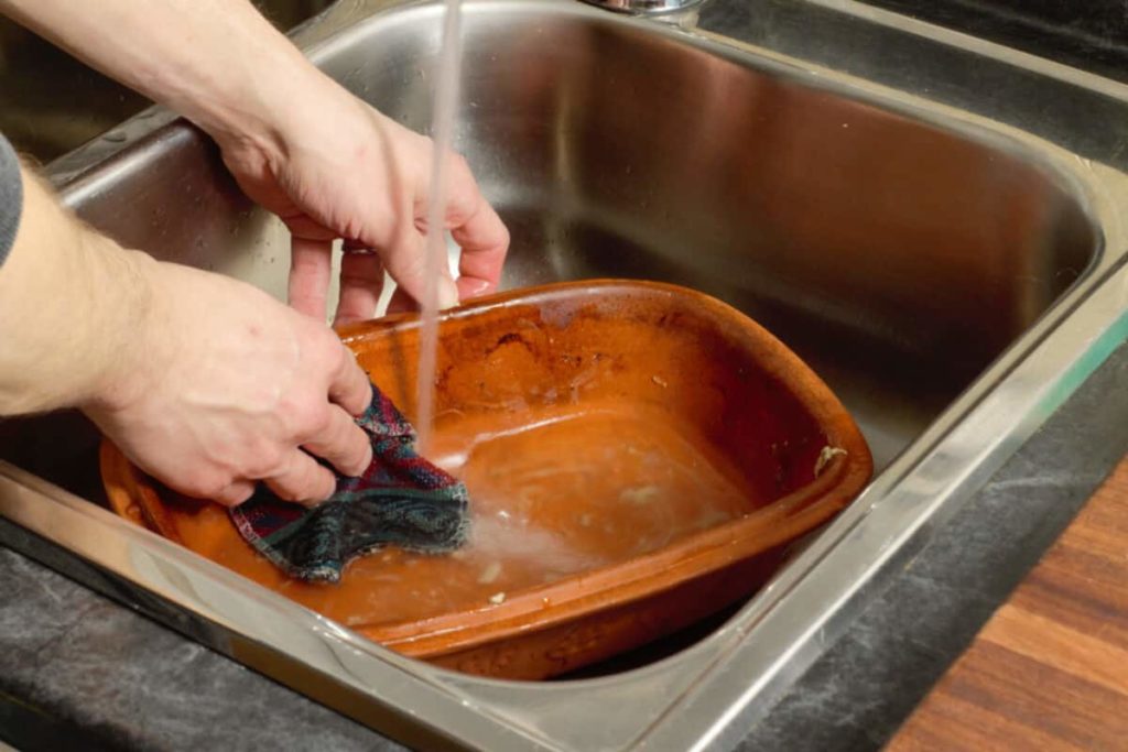  schrubben Sie einen schmutzigen Tonbäcker mit heißem Wasser, um ihn zu reinigen